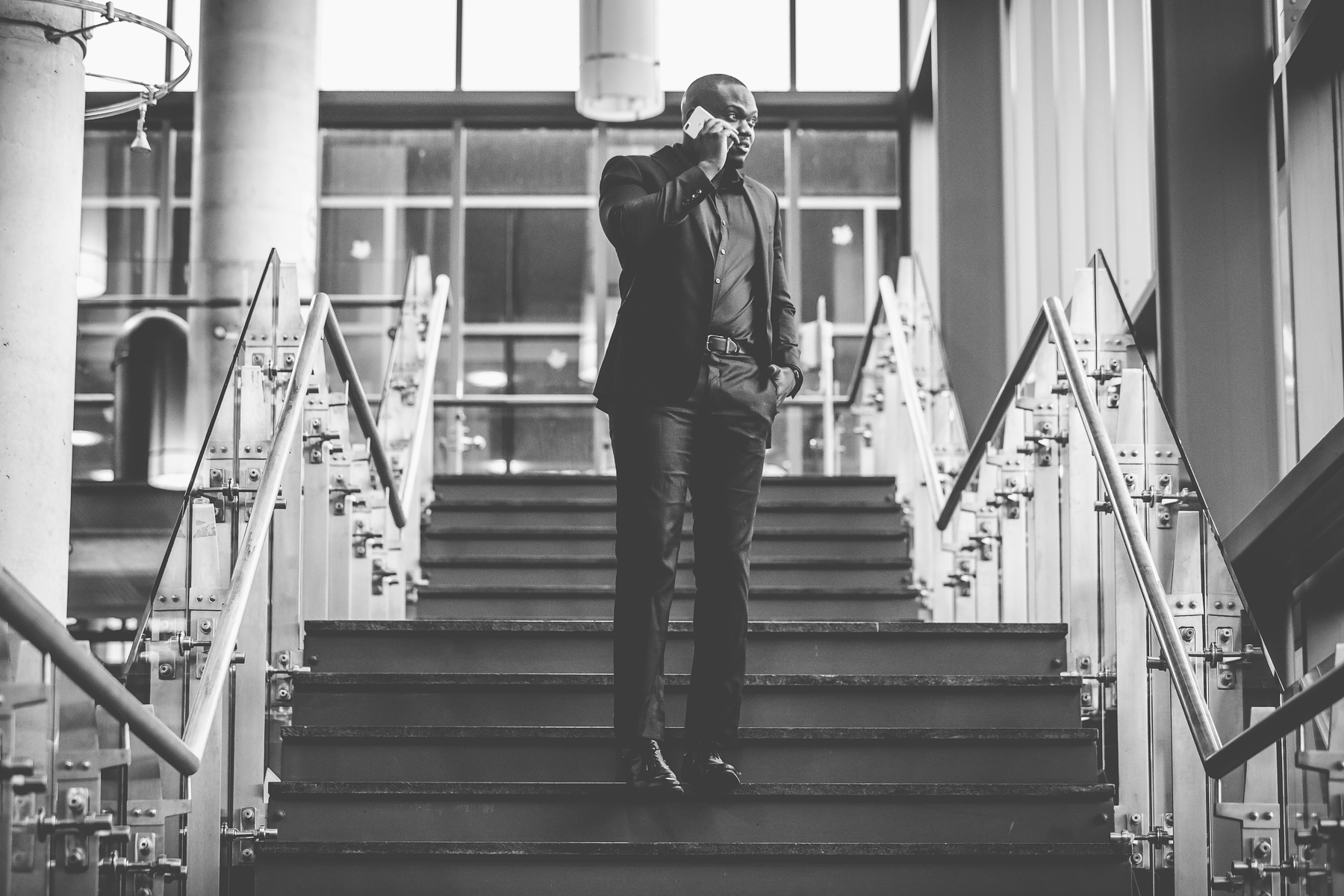 Black and white photograph of Kenneth Toppin on a phone call in an office atrium
